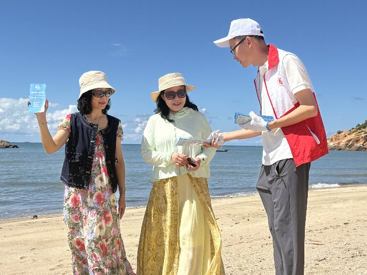 圖為凈灘志愿者向游客群眾派發宣傳單.jpg
